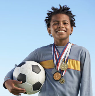 Boy holding football with medals around neck